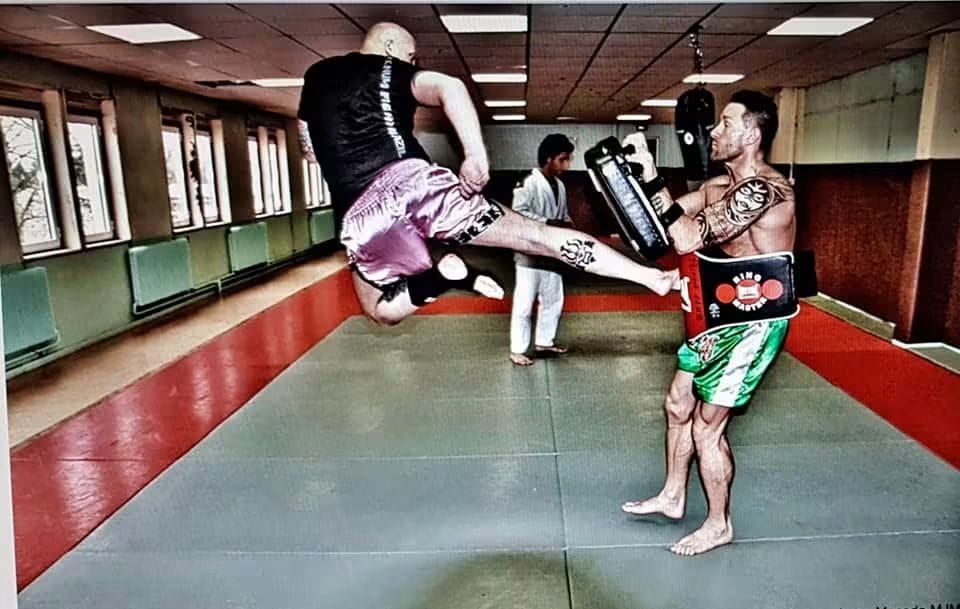 Genou sauté sur un bouclier de frappe pendant un entraînement de boxe thaï.
